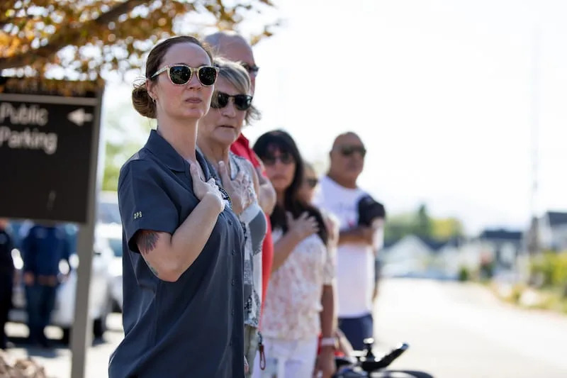 Community members place their hands over their hearts as the hearses carrying the bodies of fallen Trenmont-Garland police officers, Sgt. Lee Sorensen and officer Eric Estrada, depart the Utah State Medical Examiner's Office in Taylorsville to Garland and Logan on Monday. | Rio Giancarlo, Deseret News