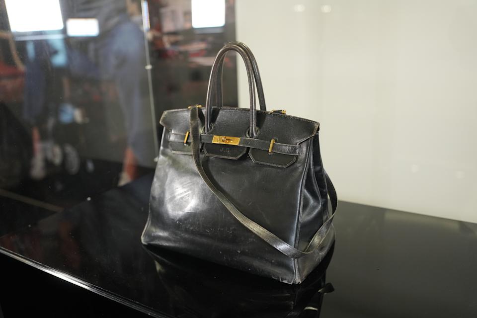 El bolso Hermès Birkin de cuero negro original de Jane Birkin, que muestra cuero arrugado, herrajes oxidados en tono dorado, marcas visibles y una correa de hombro desgastada. (Photo by Edward Berthelot/Getty Images)