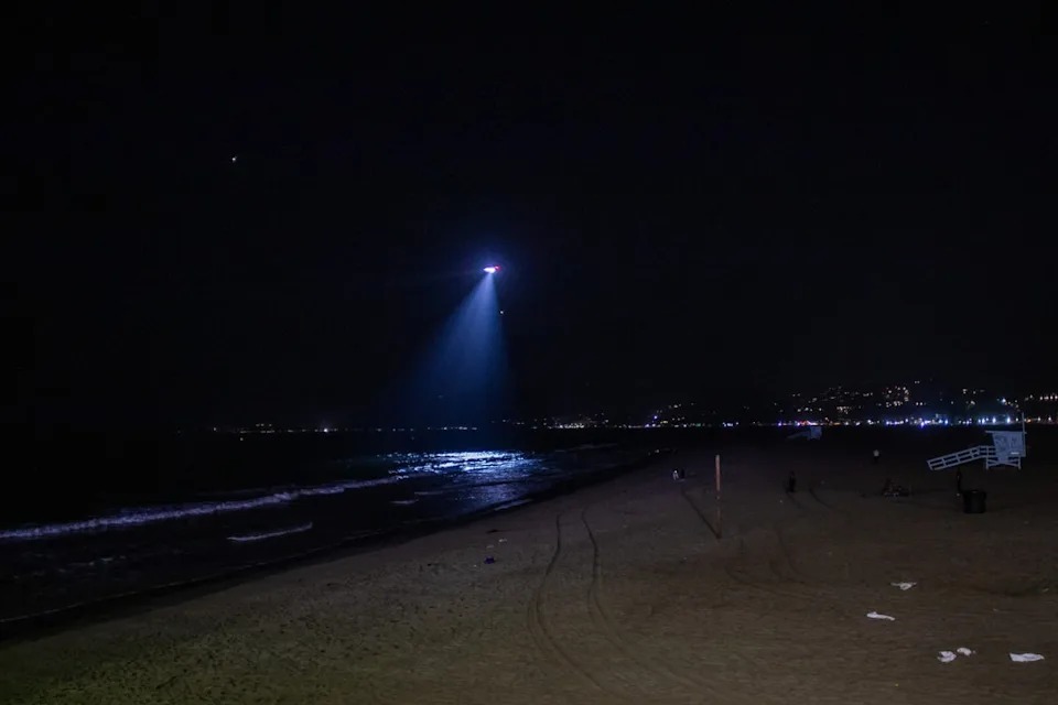 A Los Angeles police department helicopter flies over Santa Monica beach, California, amid a tsunami warning on 29 July (AFP via Getty Images)