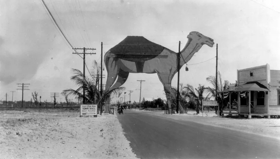 In May 1928, a Shriners convention in Miami attracted members from all over the United States who drove down Dixie Higghway. Boca Raton city fathers decided to erect this camel, a Shrine symbol, as a special welcome. The sign suggests a visit to the "new Town Hall and restrooms for the ladies and gentlemen." Today this is the site of Dixie Highway at Boca Raton Road looking north.