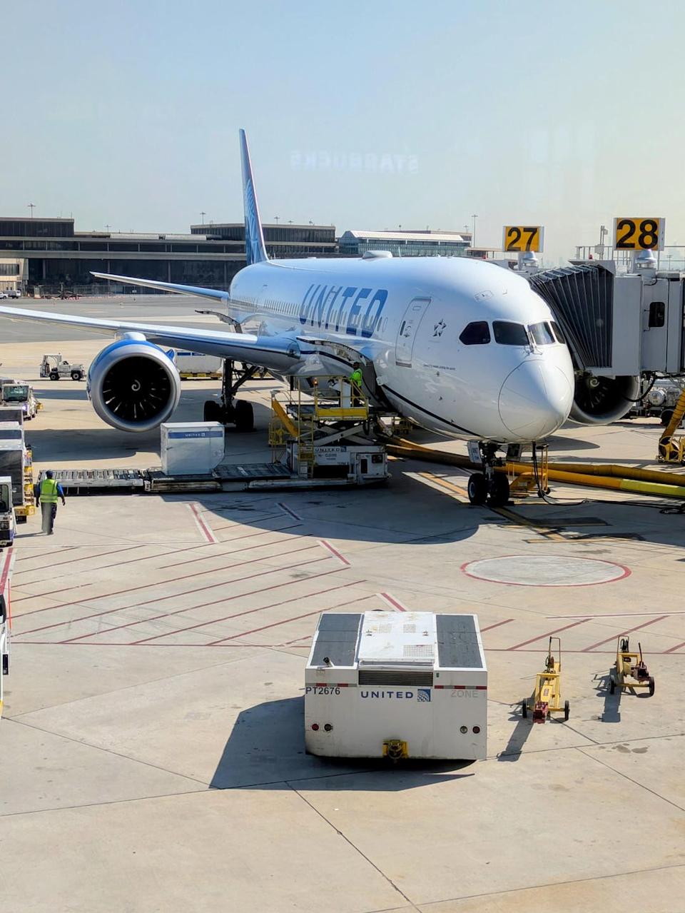 United Airlines plane at the airport gate with ground crew and baggage handlers
