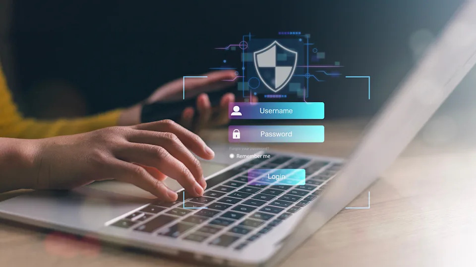 Hands typing on a laptop keyboard with a digital lock and shield graphic overlay, symbolizing cybersecurity or secure login