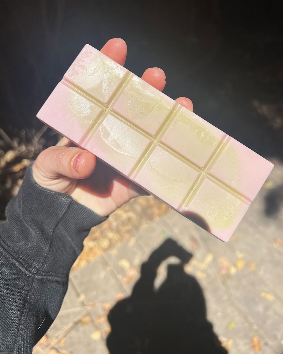 A hand holds the angel hair bar, made with flavored white chocolate dyed pink and green.