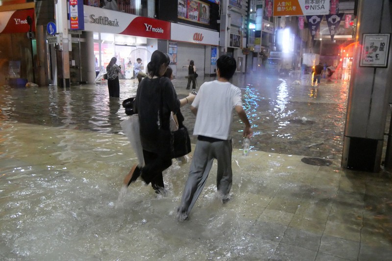 水浸しになったアーケード街を歩く人たち＝熊本市中央区で2025年8月11日午前3時8分、中村敦茂撮影