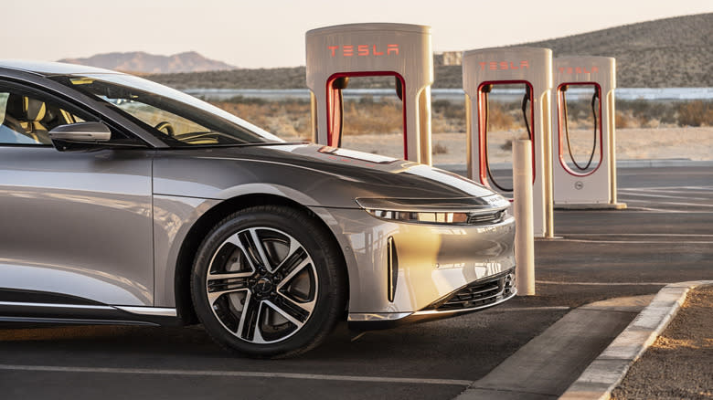 a tan Lucid Air parked at a Tesla Supercharger station