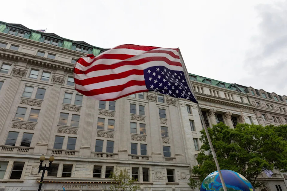 The American flag waves upside down in front of a large, ornate building