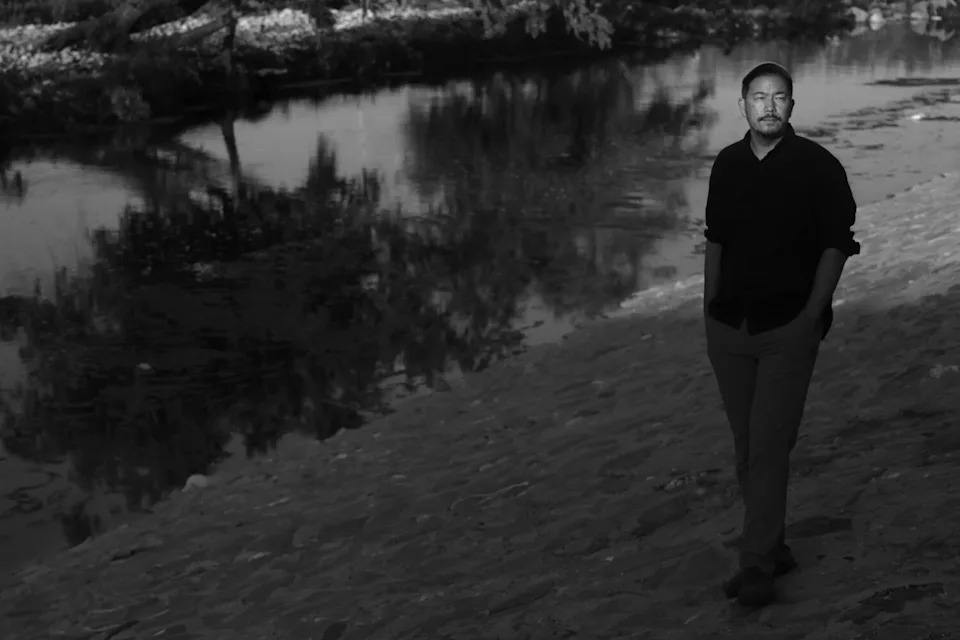 Artist and designer Rosten Woo stands near the Los Angeles River.