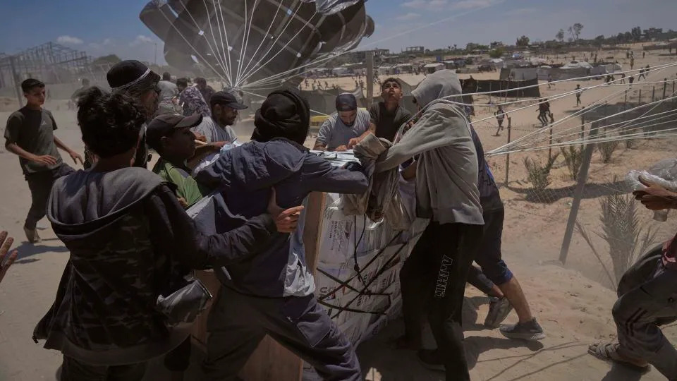 Palestinians rush to collect humanitarian aid airdropped by parachutes into Deir al-Balah, central Gaza Strip on Tuesday. - Abdel Kareem Hana/AP