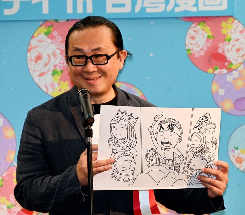 開幕式で、イラストを手にしながらあいさつする阮光民氏＝東京都港区虎ノ門の台湾文化センターで2025年8月22日、鈴木玲子撮影