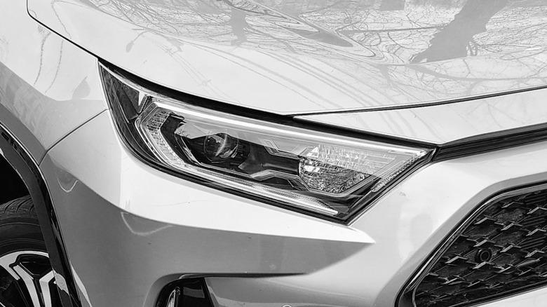 A closeup of the right headlight of a silver Toyota RAV4 Prime
