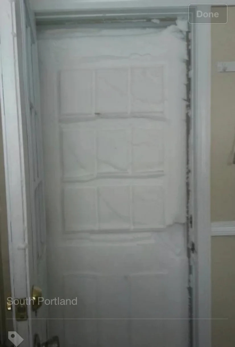 Door completely blocked by snow, visible through glass panes, in South Portland location