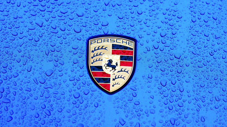 A Porsche badge in the rain