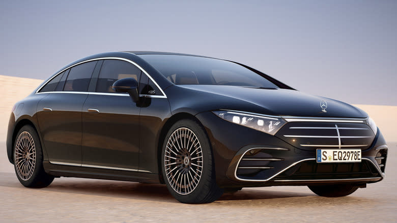 A 2025 Mercedes Benz EQS parked on sand with a gray sky in the background