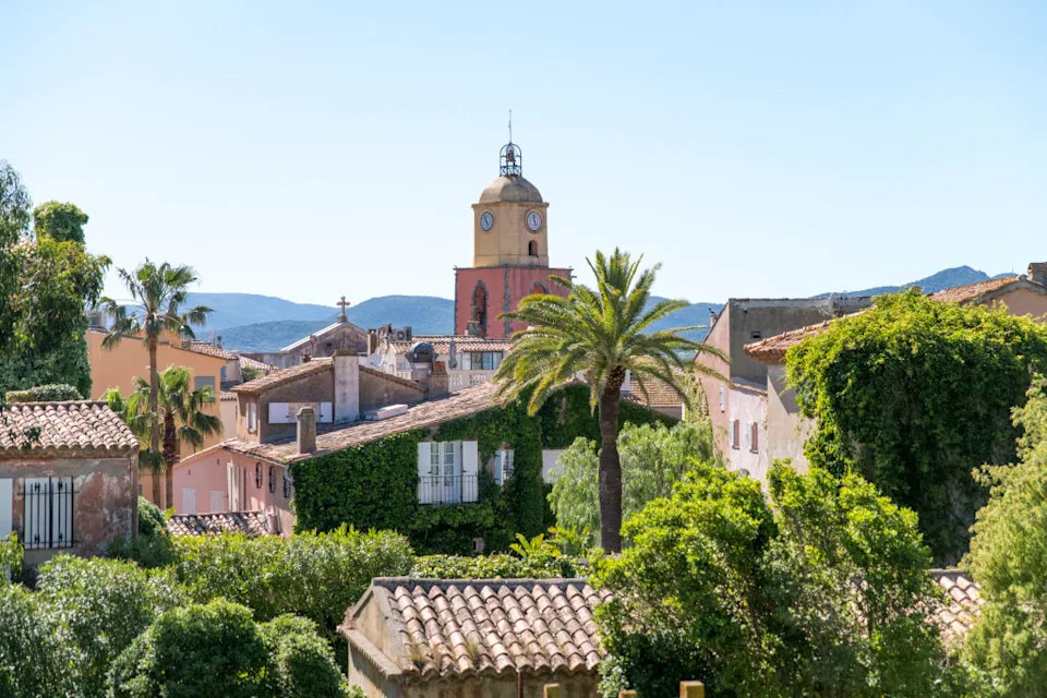 PRODUCTION – 25 May 2021, France, Saint-Tropez: The tower of the church “Église Paroissiale Notre Dame de l’Assomption” rises up behind houses and trees. Photo: Sebastian Sinterhauf/dpa (Photo by Sebastian Sinterhauf/picture alliance via Getty Images)