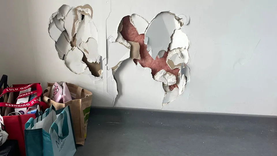A view of a damaged wall with bags to the side