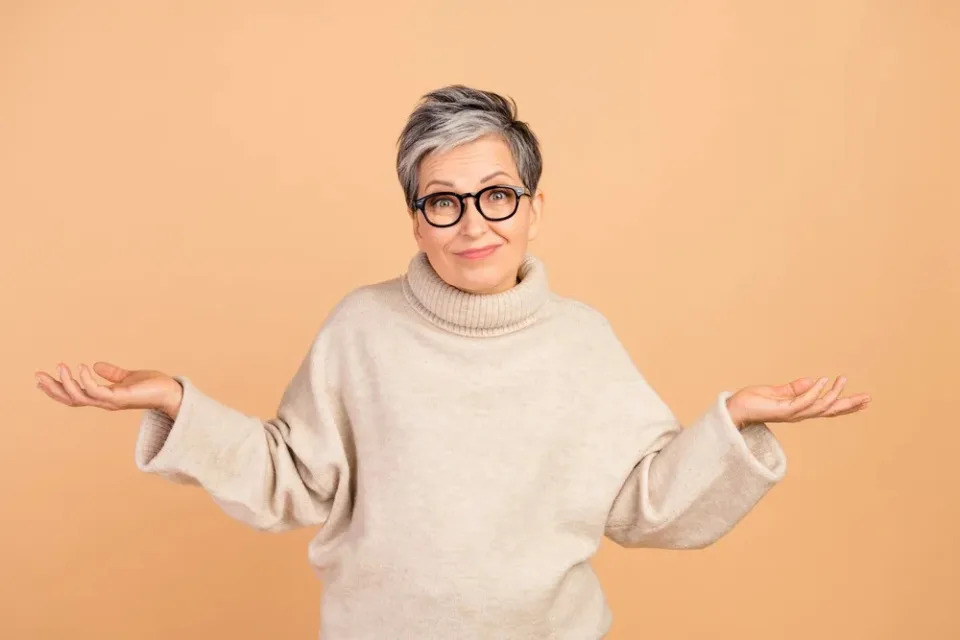 Older woman gesturing and wearing glasses.