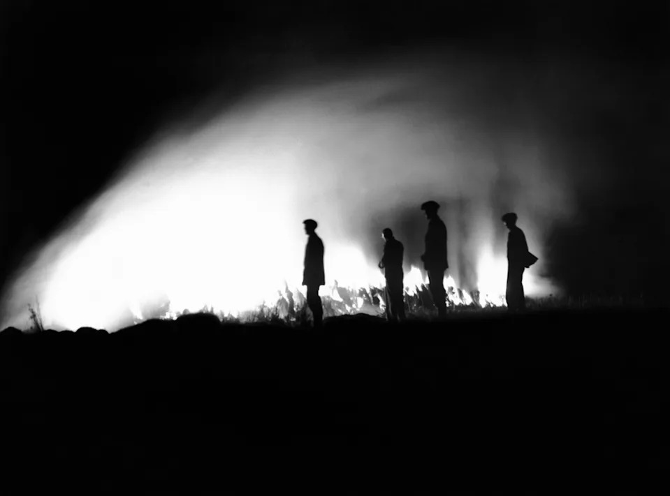 Silhouetted figures stand in front of a bright light, creating dramatic shadows