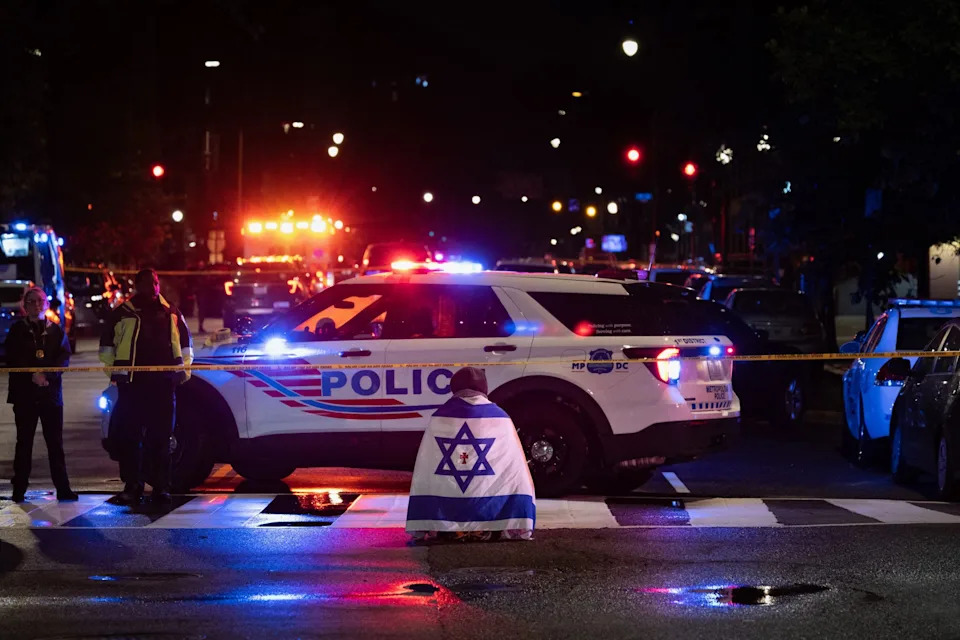 A bystander prays while wearing an Israel flag