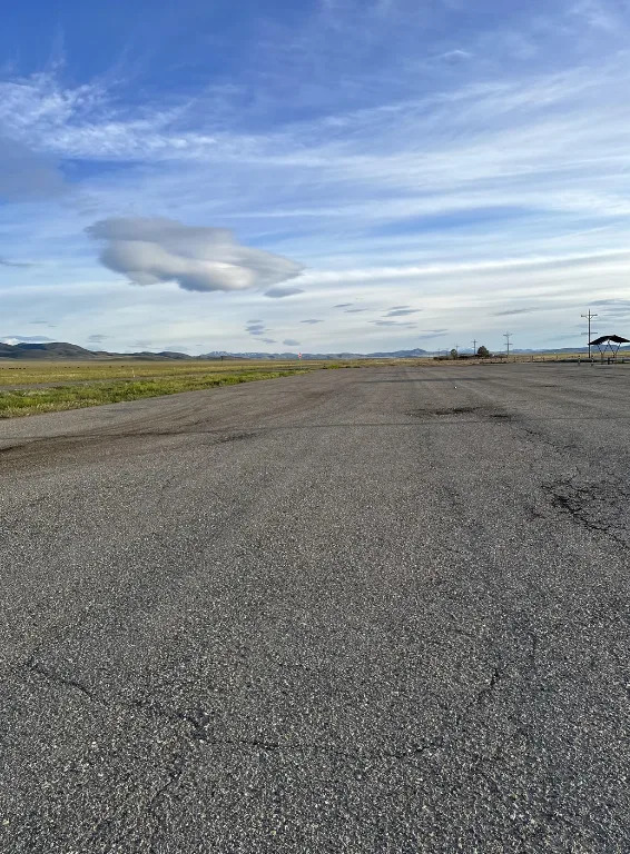Empty road under a cloudy sky stretching towards distant mountains on the horizon