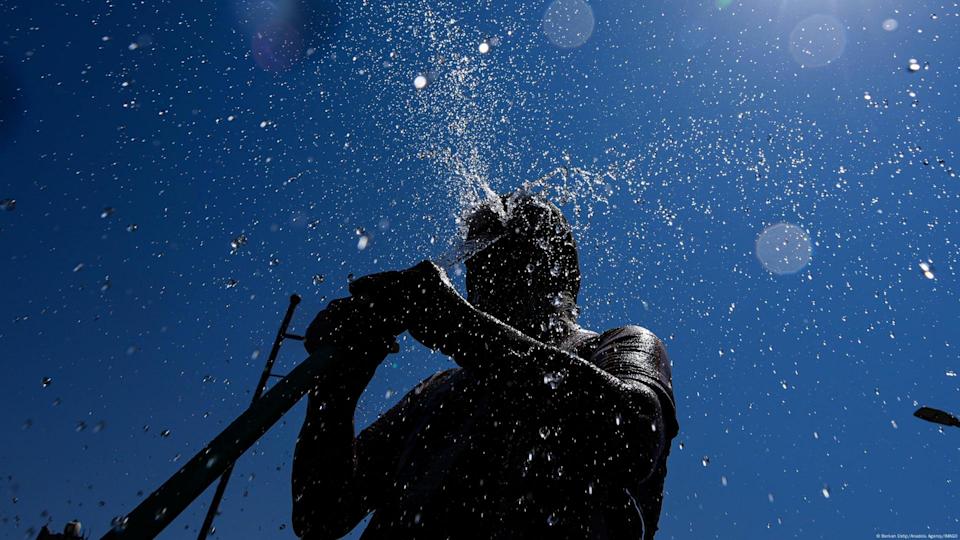 Un hombre se refresca con una manguera bajo el sol abrasador, mientras las temperaturas alcanzan los cuarenta y dos grados centígrados en Esmirna, donde el calor extremo ha dejado los espacios públicos prácticamente desiertos. (23.07.2025)