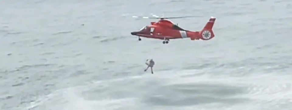 The rescue swimmer and girl are carried back up into the helicopter.