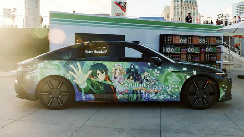 An Afeela sedan, wrapped in itasha for an anime called 'The Brilliant Healer's New Life In The Shadows'