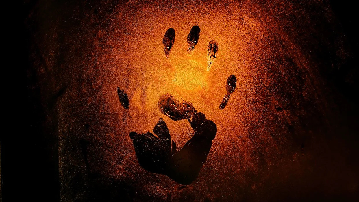 handprint on the misted glass, the red light of a lantern on the background