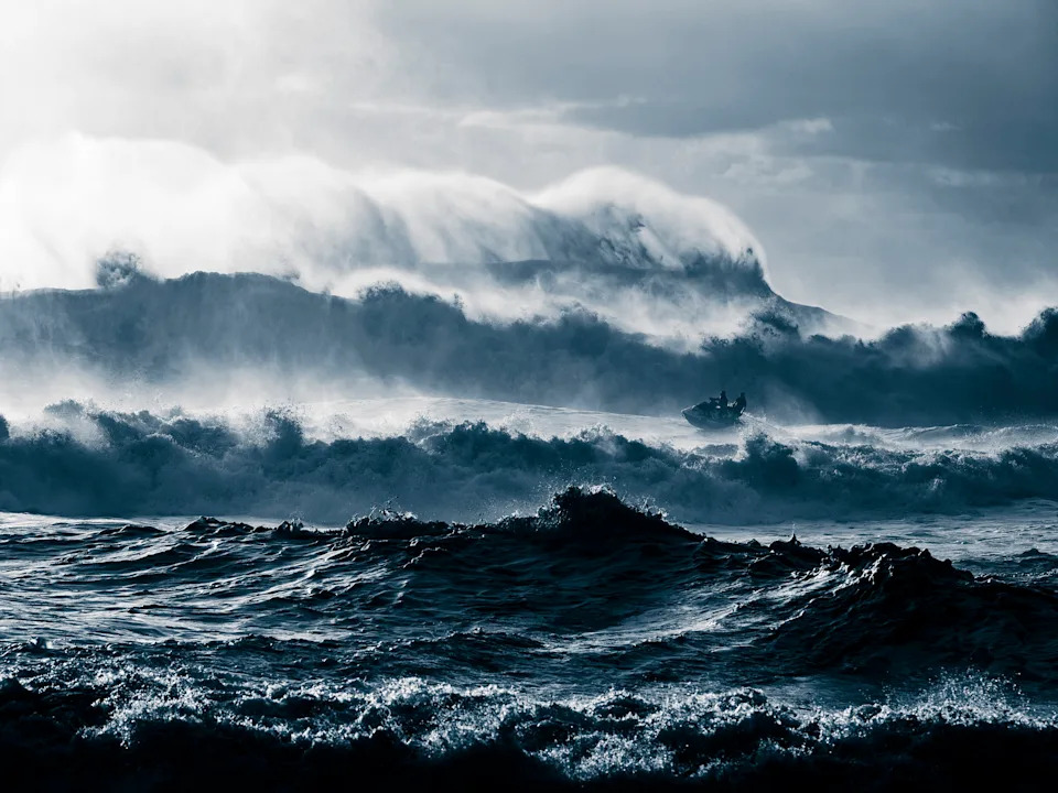 People ride a jet ski through rough surf.