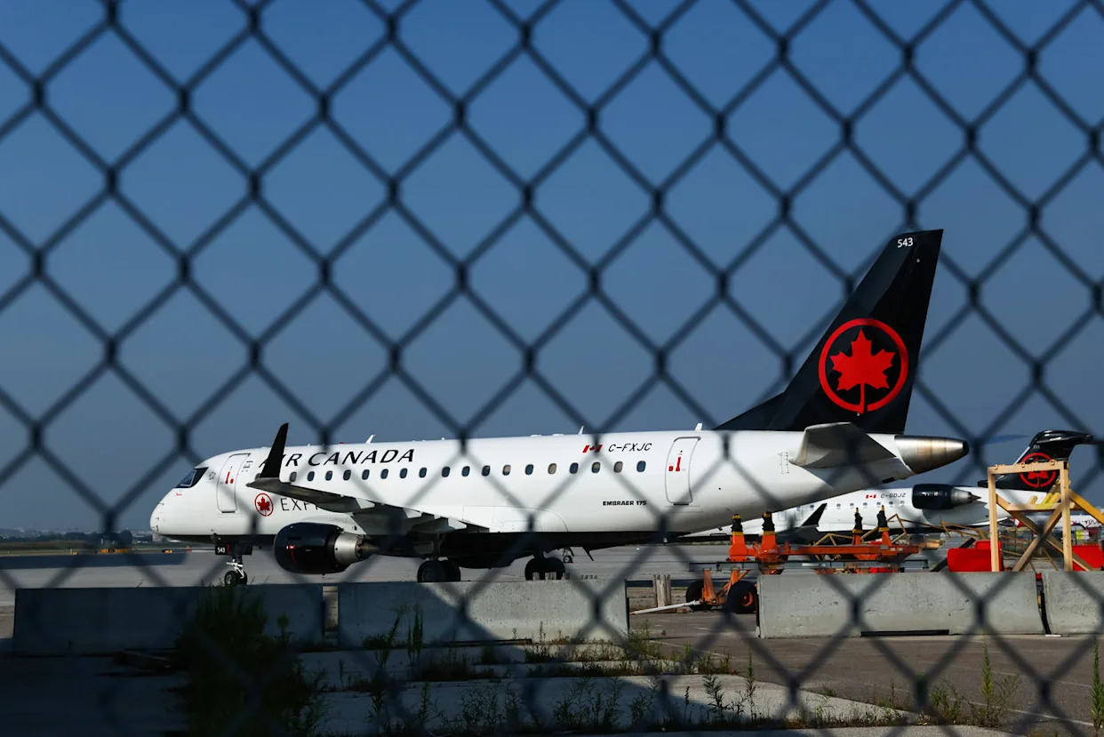 An Air Canada plane parked on the tarmac outside, pictured behind a chainlink fence (Cole Burston / Getty Images)