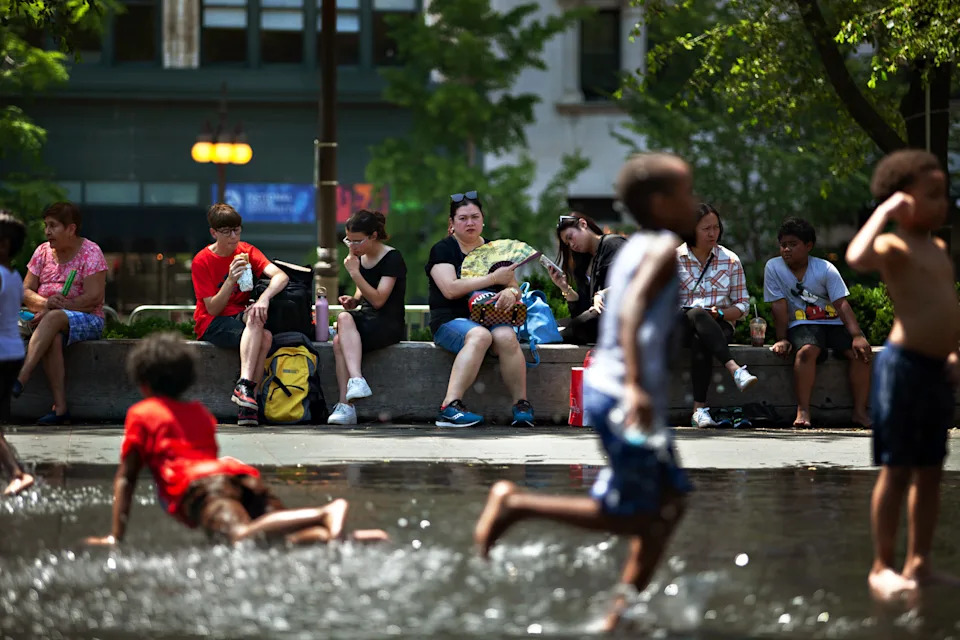 Vincent D. Johnson/Xinhua via Newscom - PHOTO: People sit in the shade as children play with water in downtown Chicago on June 14, 2022.