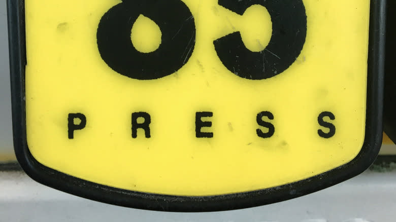A yellow 85 octane gas station button with the word "press"