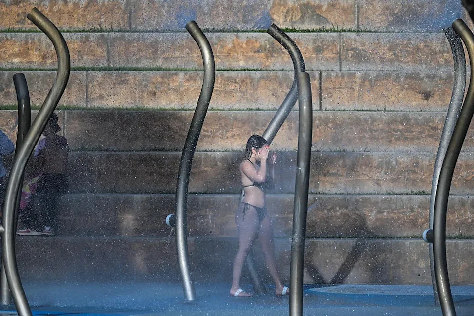 A woman washes her face on the splash pad as the region is under an extreme heat warning in Miami Beach, Florida, on July 25, 2025.