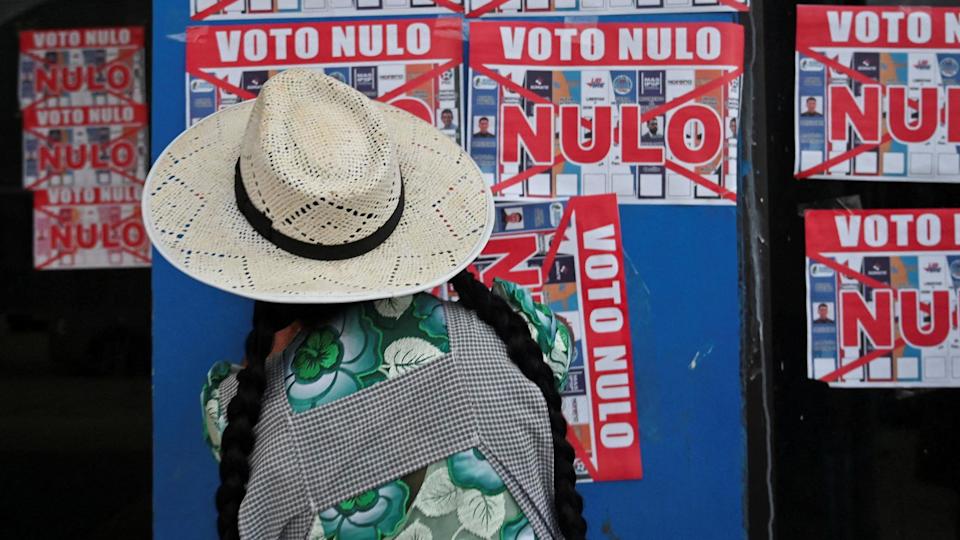Una mujer pega un cartel que dice "Voto Nulo" en la pared exterior de una casa de campaña antes de las elecciones generales de Bolivia, en Chapare, Bolivia, el 2 de agosto de 2025.
