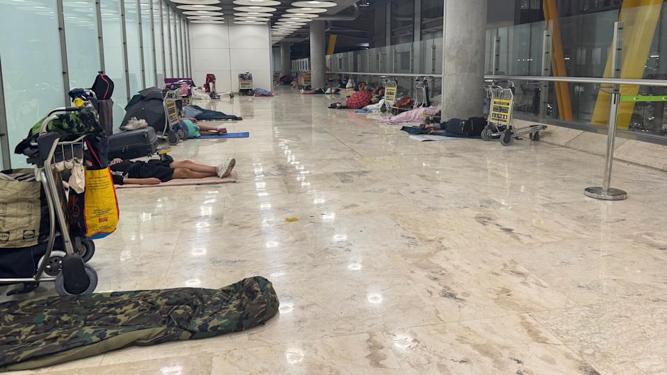Personas durmiendo en un pasillo del aeropuerto de Barajas.