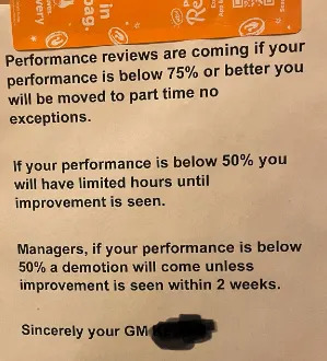 Notice on door about performance reviews, stating potential demotion if performance is below certain thresholds, signed by GM