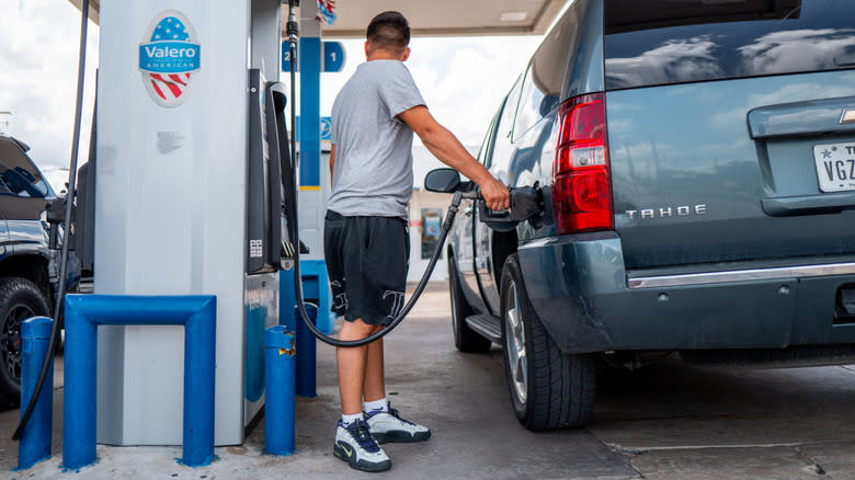 A man refueling an SUV at a gas station