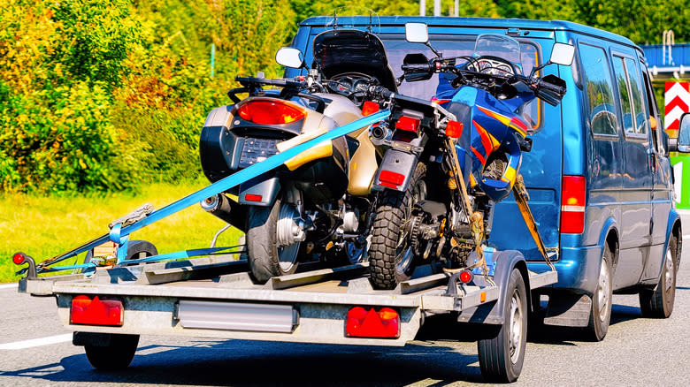 Two motorcycles strapped on a trailer.