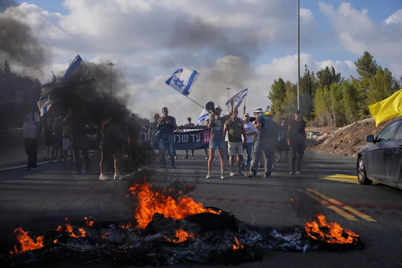 Demonstrators block a road during a protest demanding the immediate release of hostages held by Hamas and calling for the Israeli government to reverse its decision to take over Gaza City and other areas in the Gaza Strip, near Jerusalem, Israel, Sunday, Aug. 17, 2025. / Credit: Ohad Zwigenberg / AP