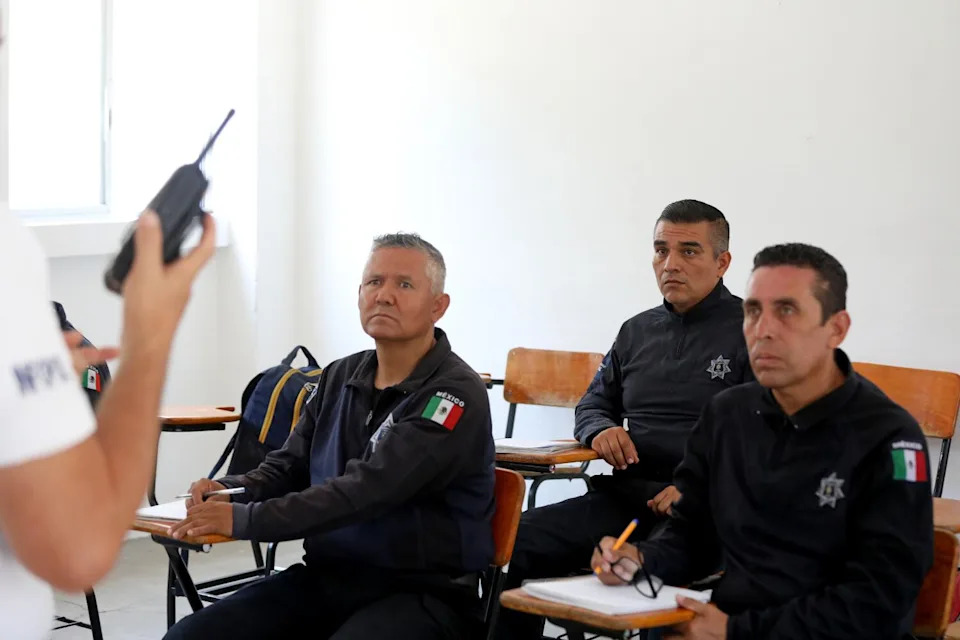 Police officers sit in a classroom.