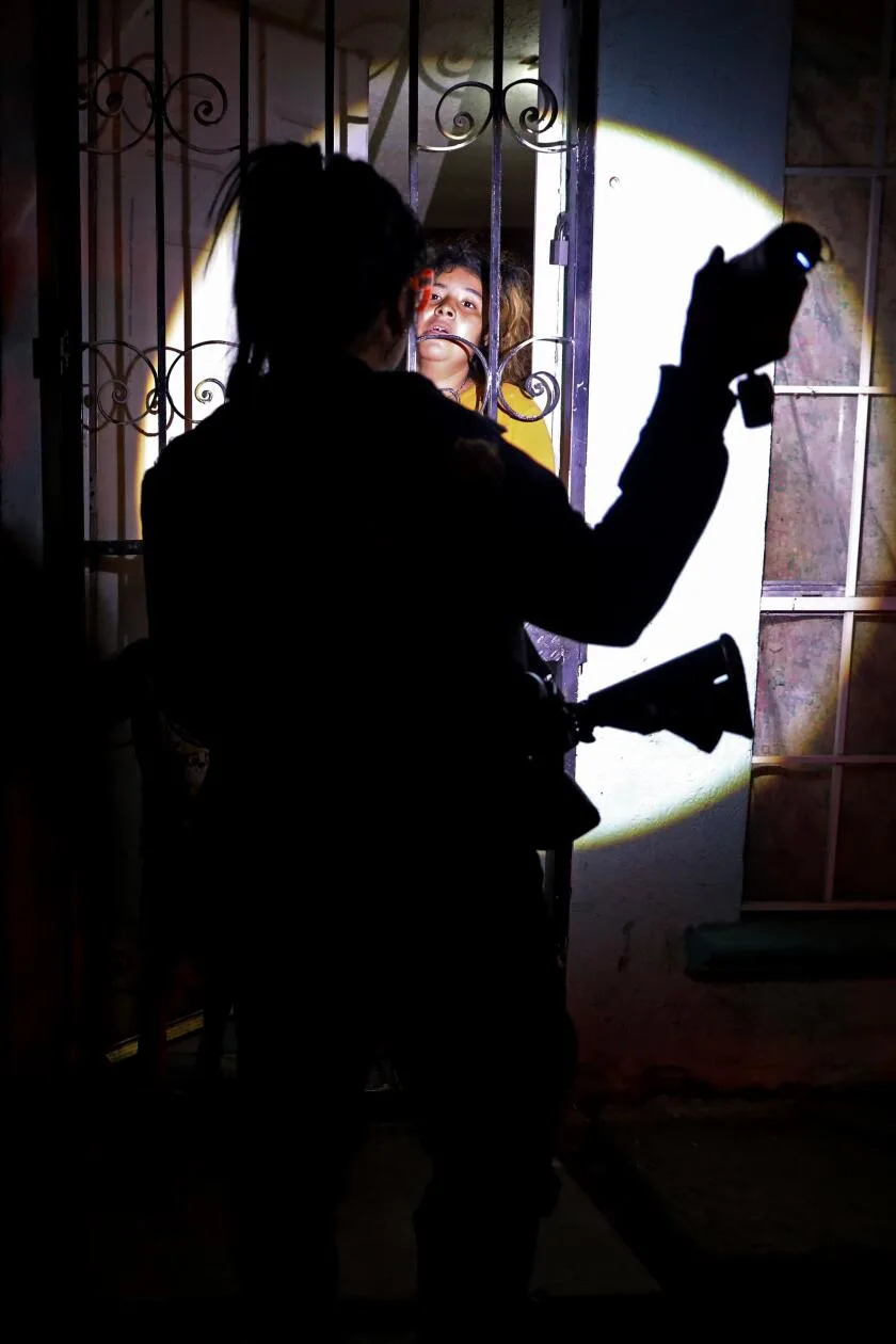 A silhouetted police officer questions a woman.