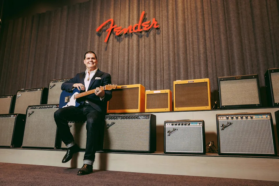 Edward Cole poses in front of a wall of Fender amps.