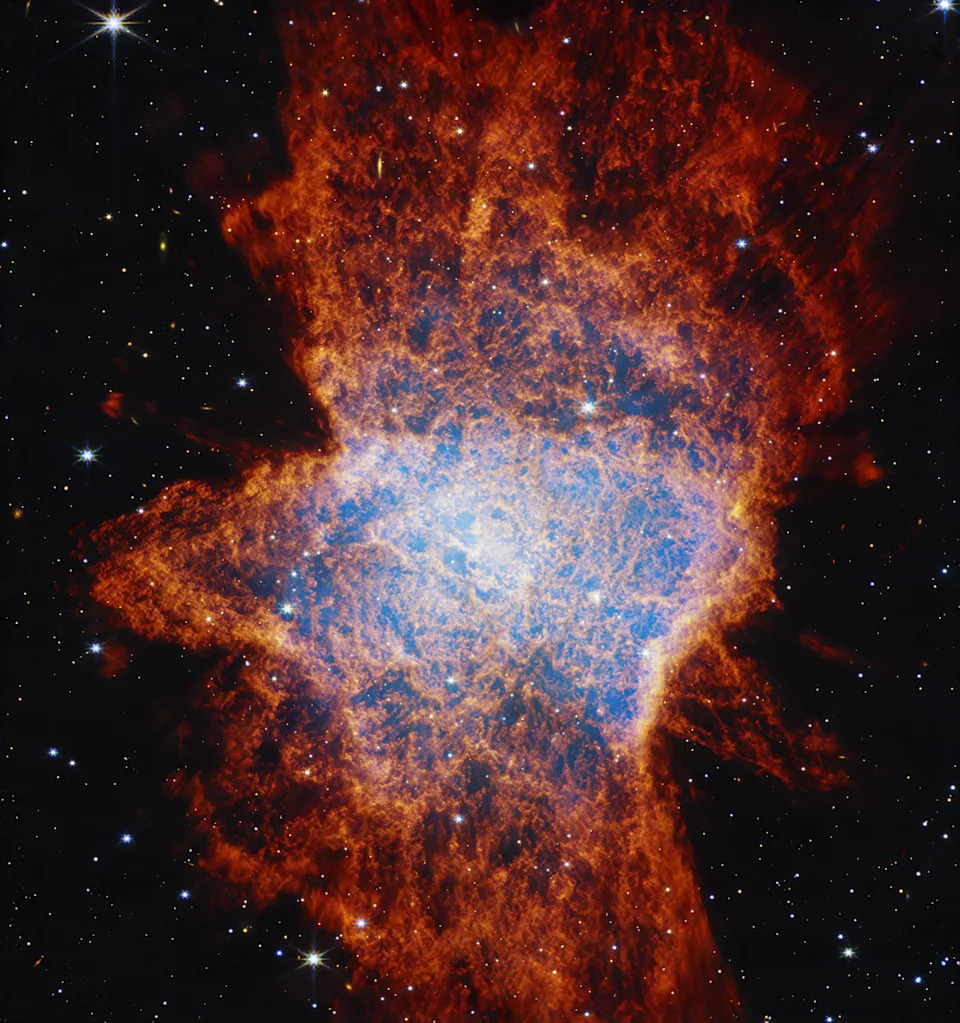 A glowing nebula, made of blue and red gas clouds with glowing stars, stands out in the darkness of space