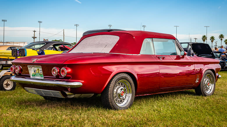 A red 1962 Chevrolet Corvair Monza Spyder with a red convertible top parked on grass.