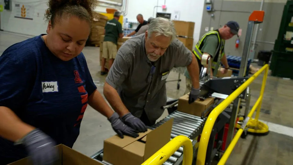 Volunteers work the supply line packing boxes of food at the Community Food Bank of Southern Arizona.  - CNN
