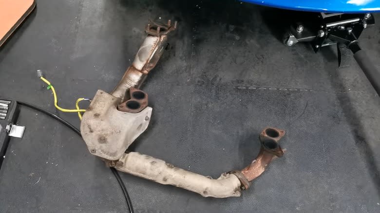 A set of stock Subaru WRX STi headers removed from the car and sitting on the shop floor