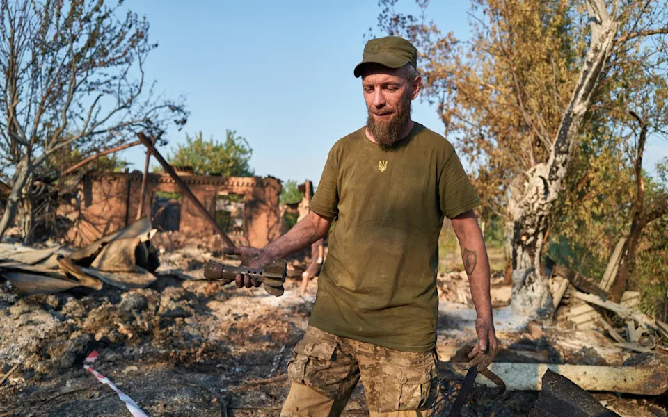 A Ukrainian soldier holds the remains of a shell at the site of a Russian Shahed drone strike