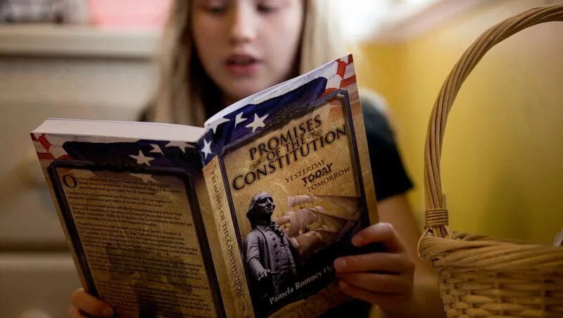 A girl reads from "Promises Of The Constitution: Yesterday Today Tomorrow" by Pamela Romney Openshaw during homeschooling at her West Jordan home on Friday, Nov. 3, 2017.