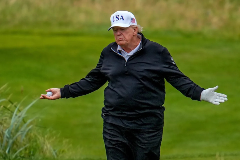 Person golfing, wearing a USA hat and gloves, with outstretched arms, on a golf course