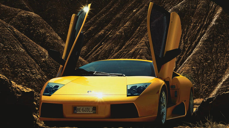 a yellow Lamborghini Murcielago parked in front of desert mountains