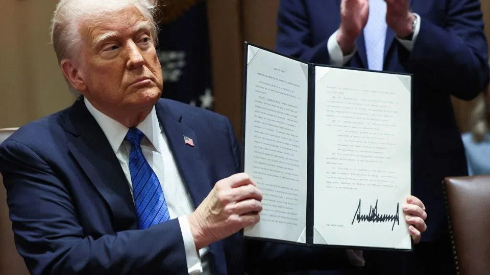 President Donald Trump holds an executive order, at the White House, in Washington, DC, on March 25. - Evelyn Hockstein/Reuters
